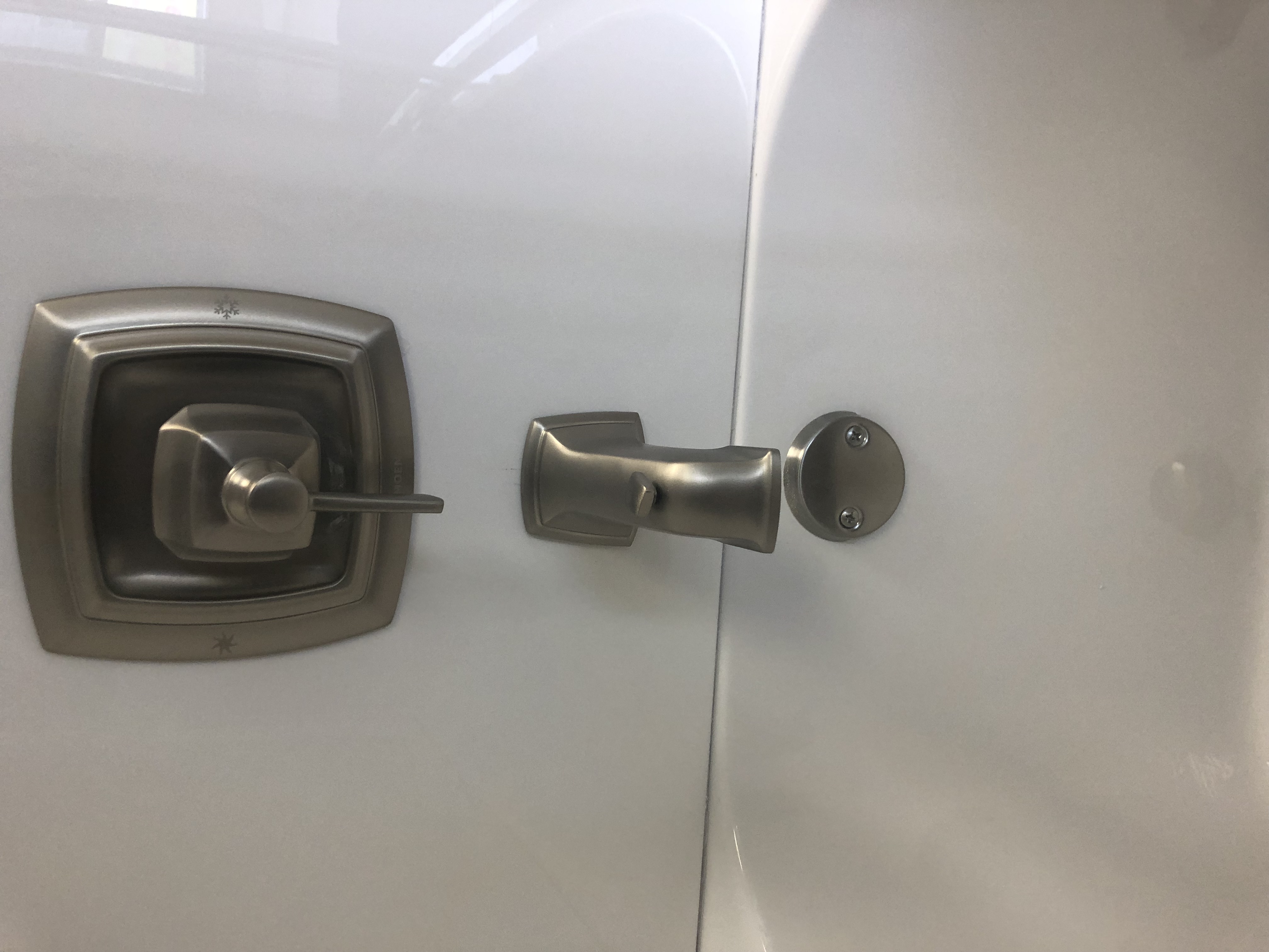 Modern bathroom with gray tiles, glass shower, wall-mounted vanity, illuminated mirror, and large windows.